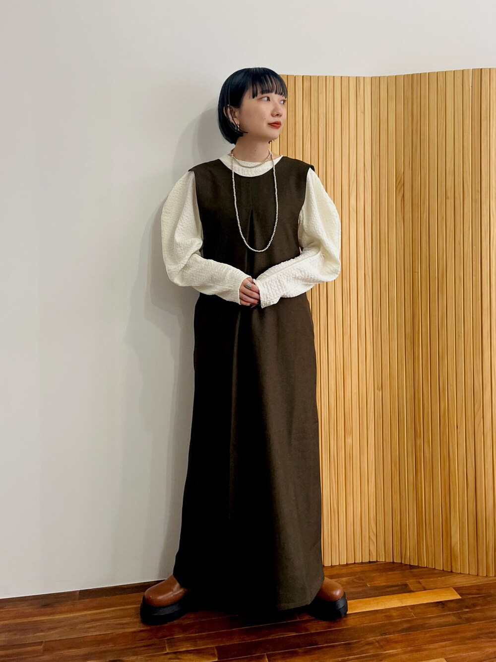 ブラウン系のワンピース、ホワイト系のTシャツ/カットソー、ブラウン系のブーツを着用したレディースの秋コーディネートの2枚目の写真