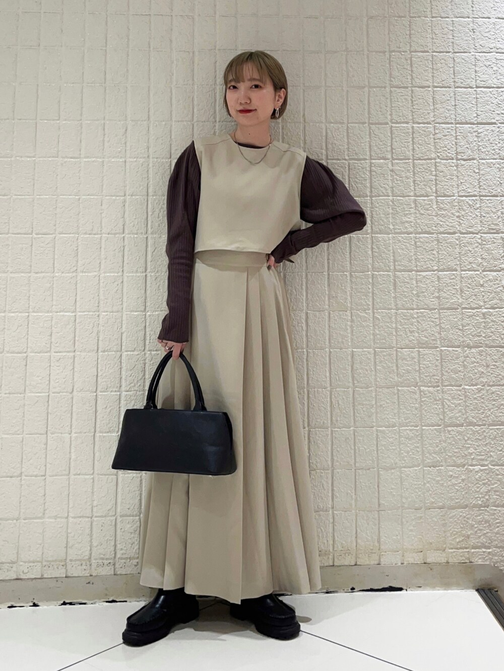 ベージュ系のワンピース、ブラック系のハンドバッグ、ブラウン系のTシャツ/カットソーを着用したレディースの秋コーディネートの2枚目の写真