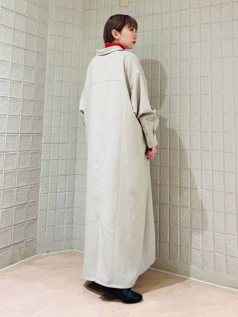 グレー系のワンピース、オレンジ系のニット/セーターを着用したレディースの冬コーディネートの3枚目の写真