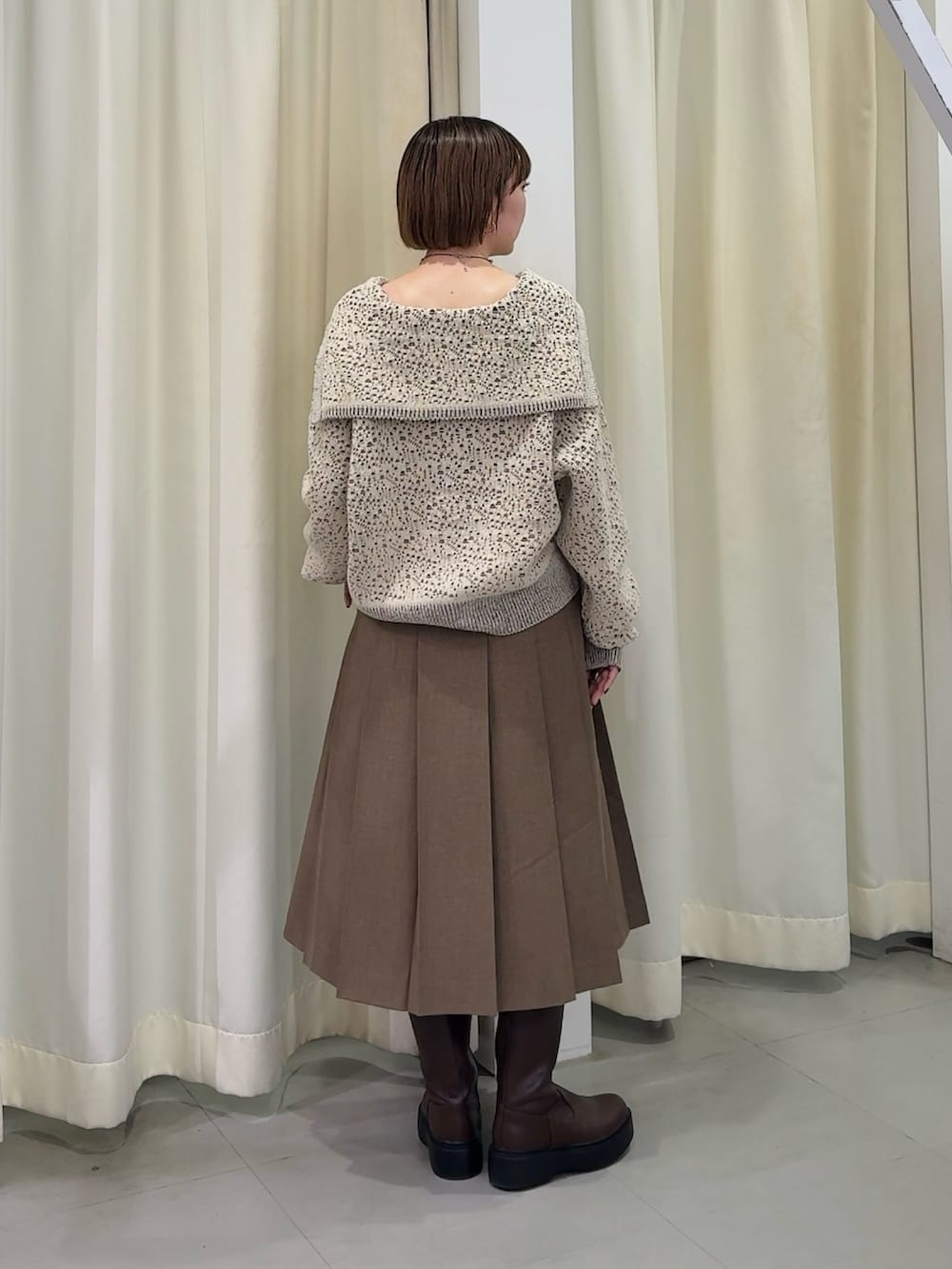 ホワイト系のニット/セーター、ブラウン系のスカート、ブラウン系のブーツを着用したレディースの秋コーディネートの2枚目の写真