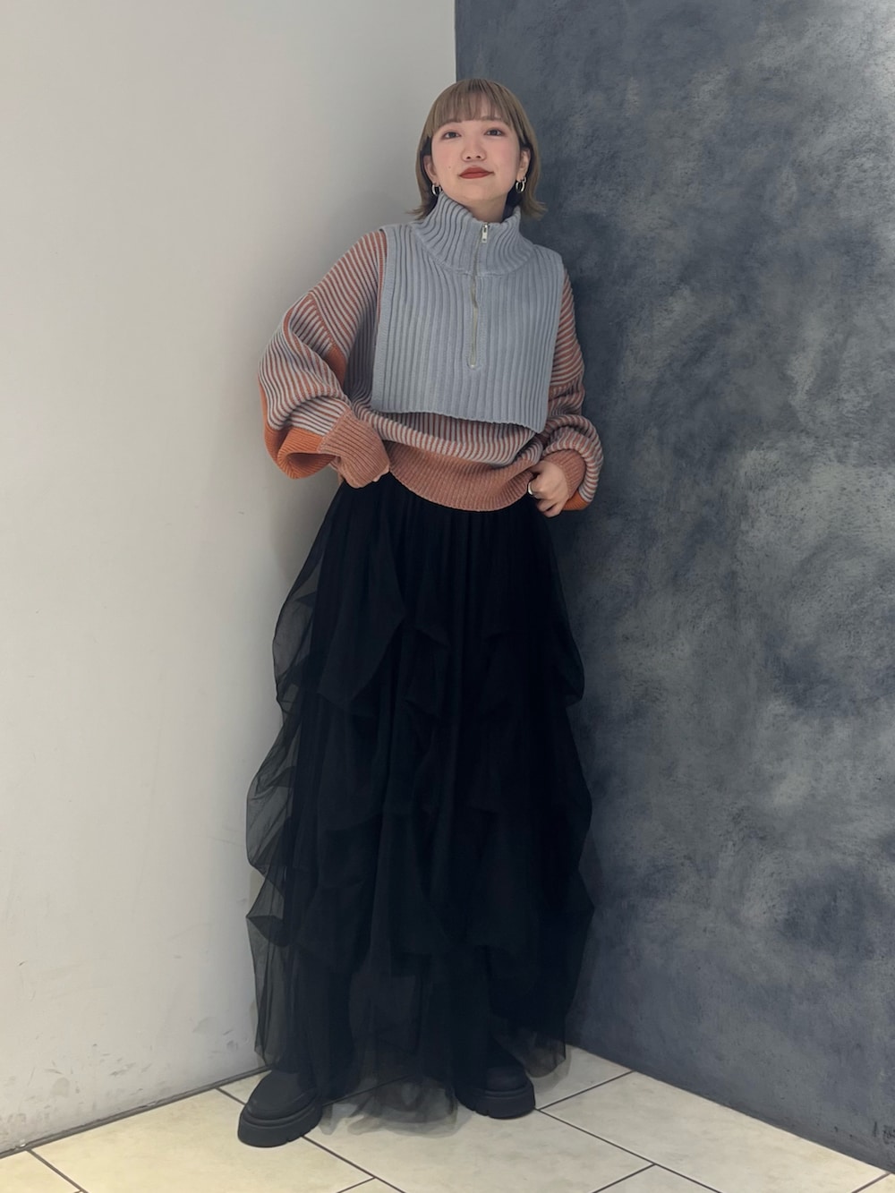 グレー系のニット/セーター、ブラック系のスカートを着用したレディースの冬コーディネートの2枚目の写真