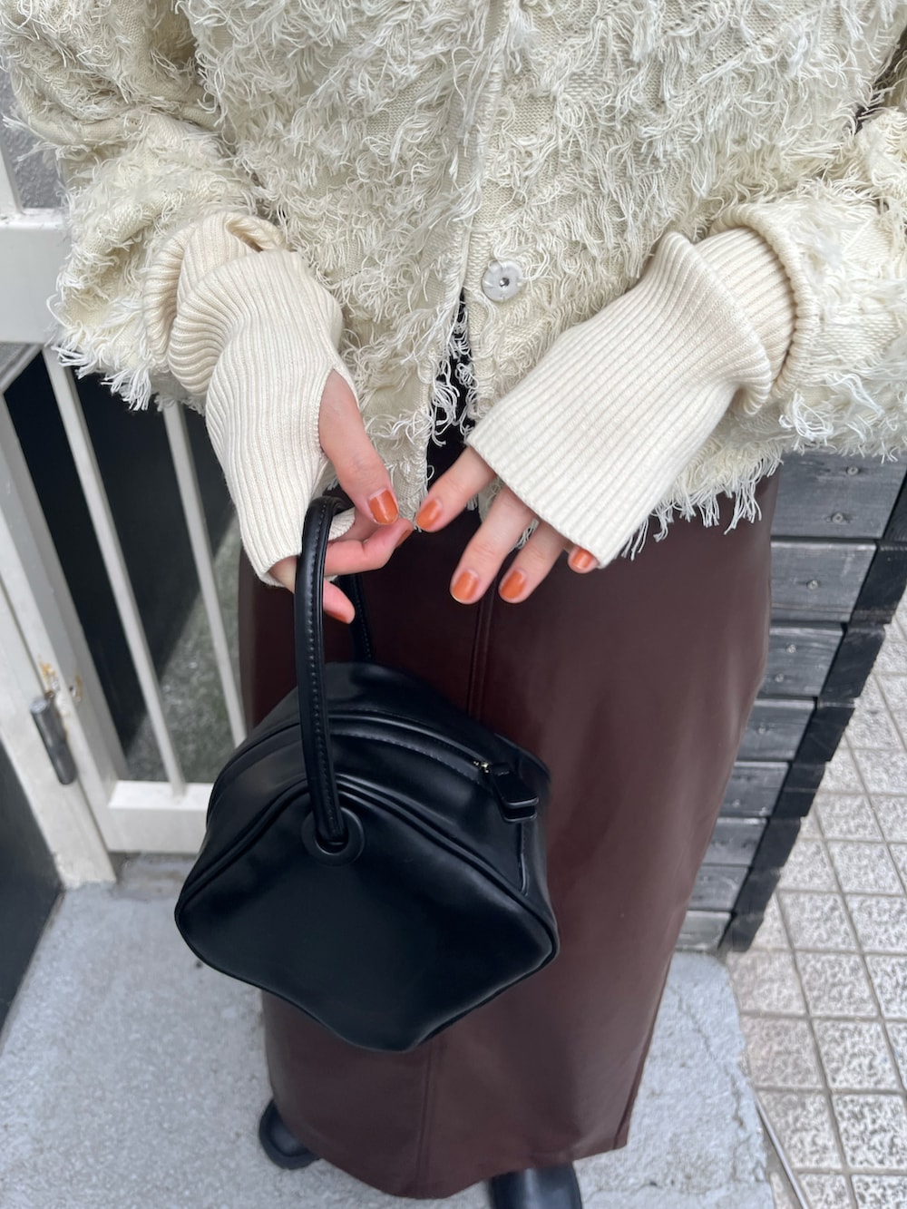 ホワイト系のカーディガン/ボレロ、ブラウン系のスカート、ブラック系のハンドバッグを着用したレディースの秋コーディネートの5枚目の写真