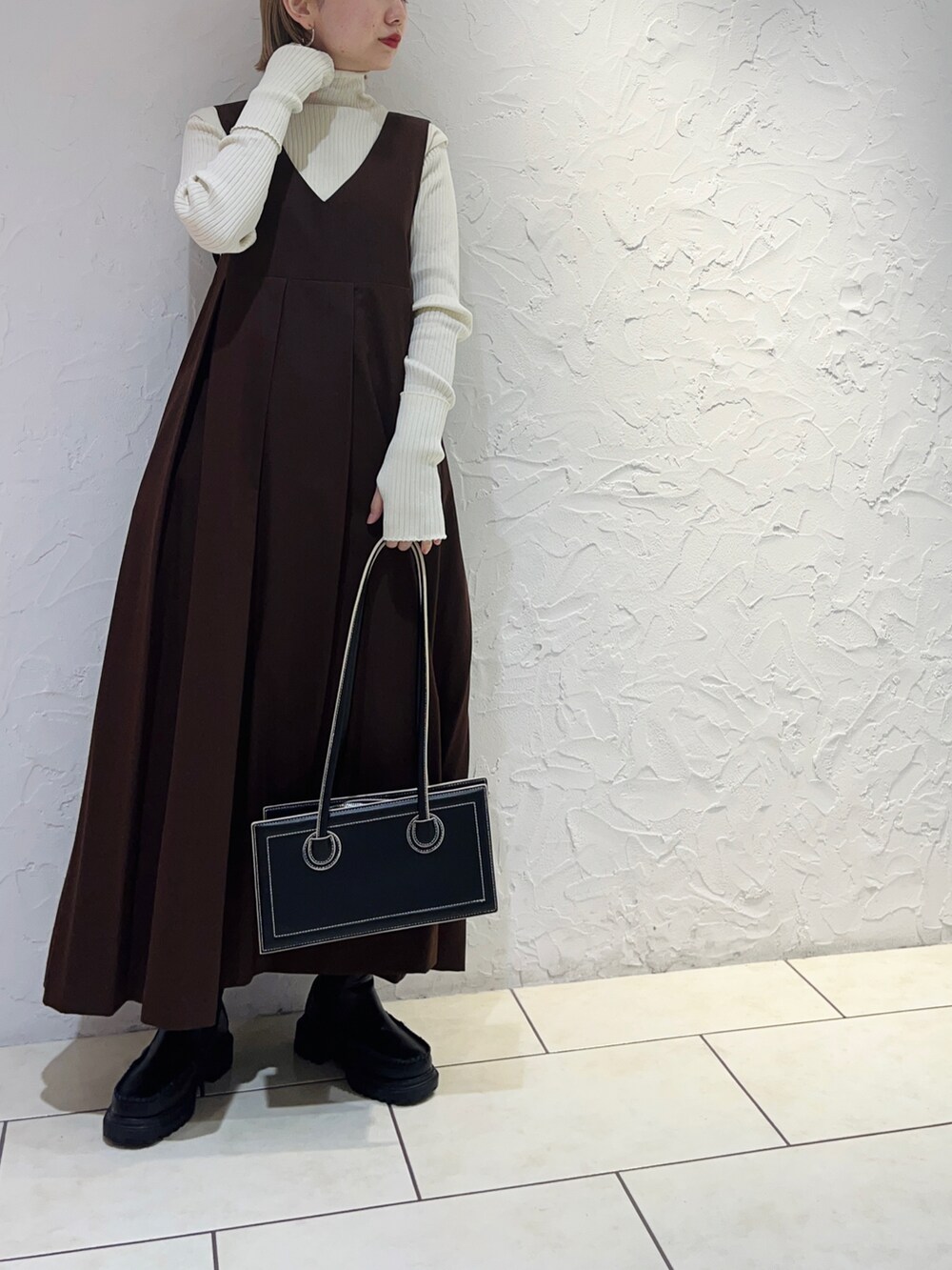 ホワイト系のニット/セーター、ブラウン系のワンピース、ブラック系のショルダーバッグを着用したレディースの秋コーディネートの2枚目の写真