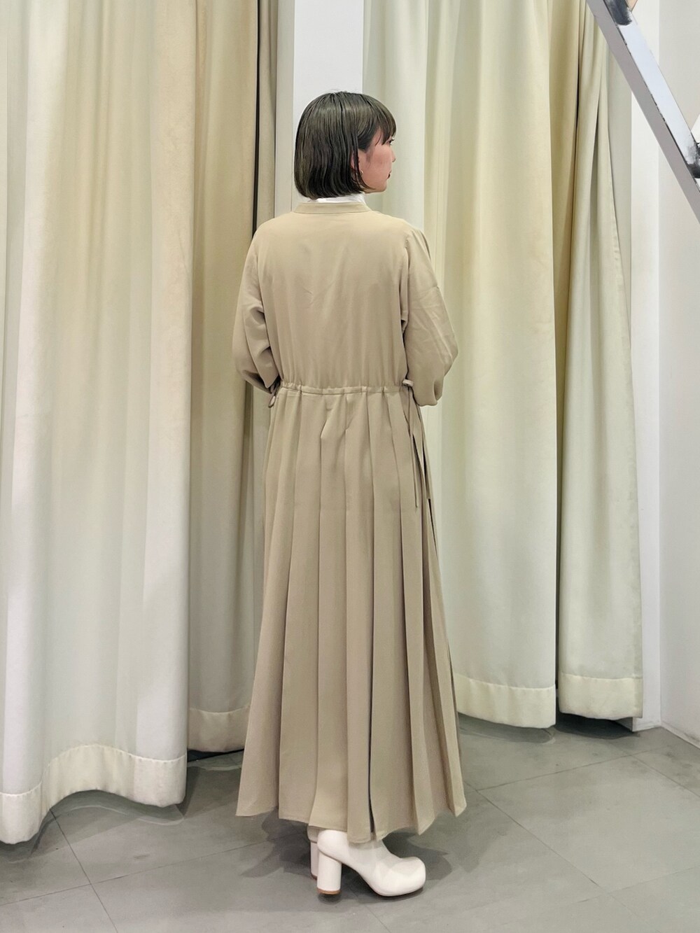 ホワイト系のブーツ、ベージュ系のワンピース、ホワイト系のTシャツ/カットソーを着用したレディースの秋コーディネートの4枚目の写真