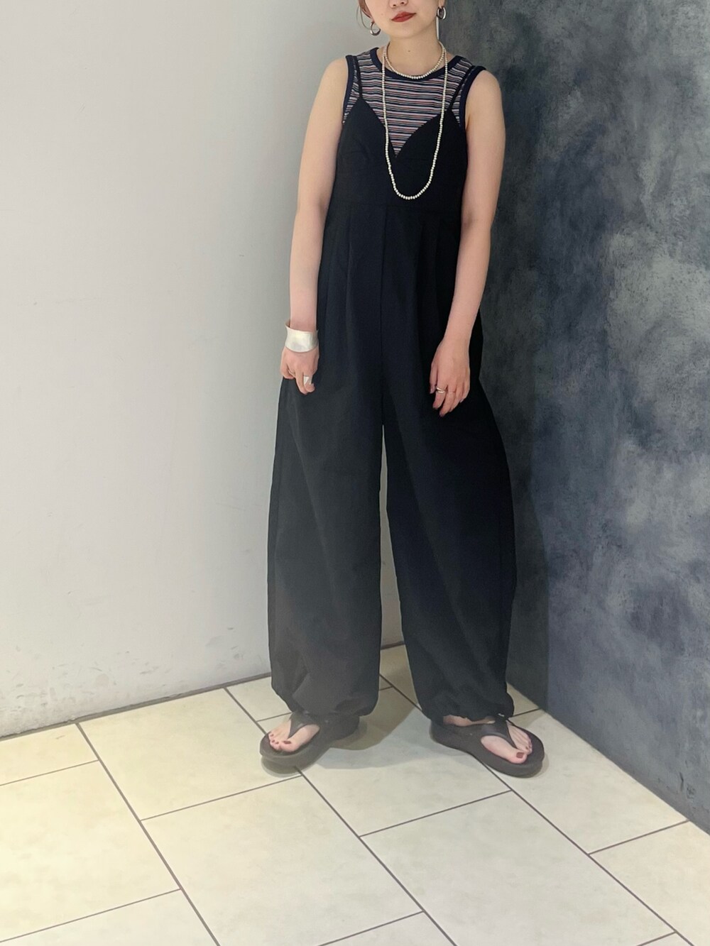 ブルー系のタンクトップ、ブラック系のサロペット/オーバーオール、シルバー系のネックレスを着用したレディースの夏コーディネートの3枚目の写真