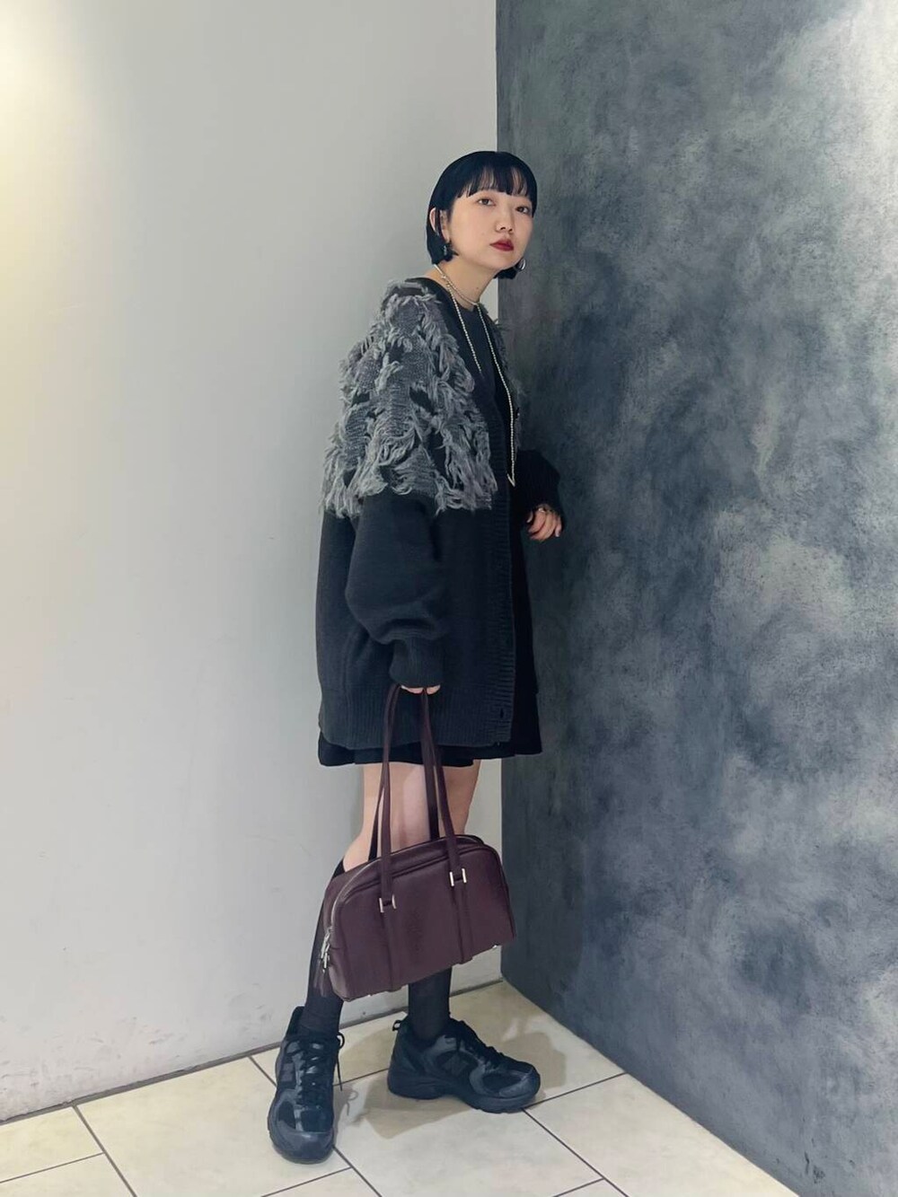 レッド系のボストンバッグ、ブラック系のワンピース、グレー系のTシャツ/カットソーを着用したレディースの秋コーディネートの2枚目の写真