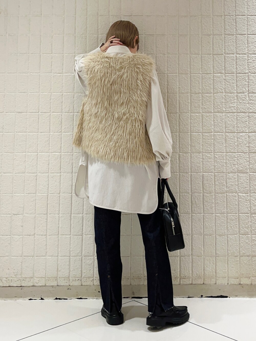 ベージュ系のベスト、グレー系のシャツ/ブラウス、ブルー系のデニムパンツを着用したレディースの秋コーディネートの3枚目の写真