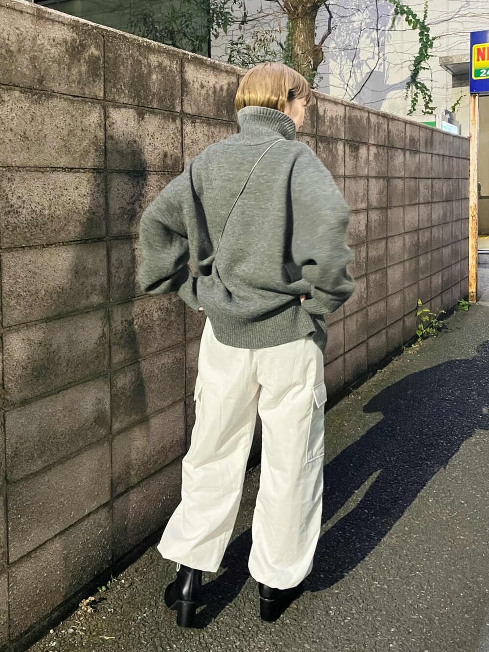 ホワイト系のカーゴパンツ、ブラック系のブーツ、シルバー系のショルダーバッグを着用したレディースの冬コーディネートの3枚目の写真