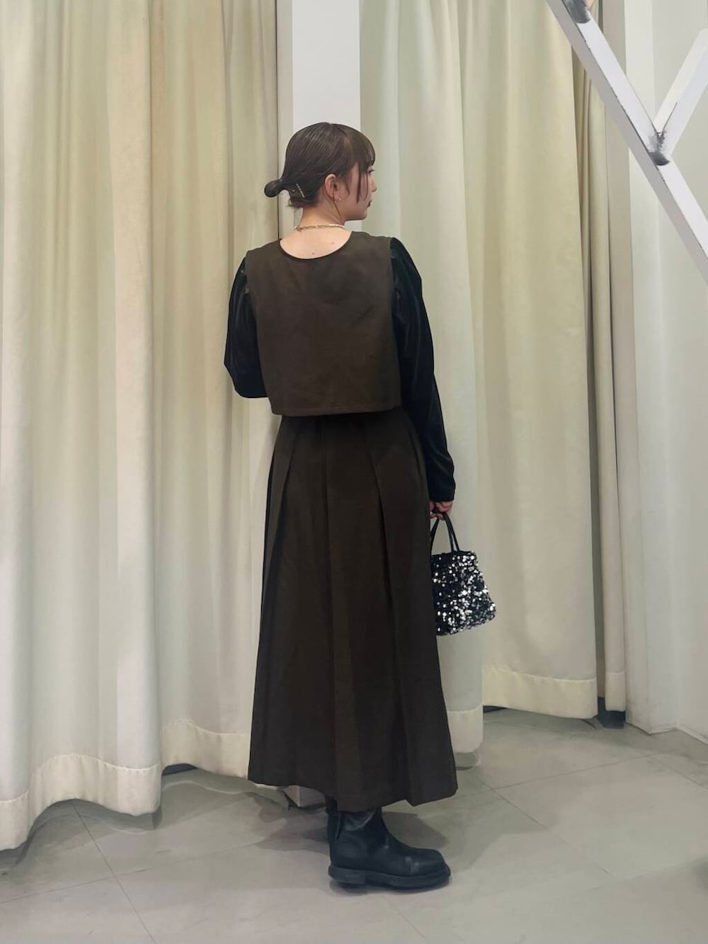 シルバー系のショルダーバッグ、ブラック系のブーツ、ブラウン系のワンピースを着用したレディースの冬コーディネートの3枚目の写真