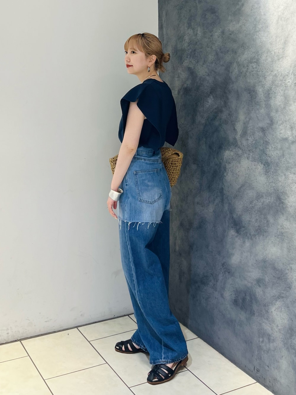 ブルー系のデニムパンツ、ブルー系のニット/セーター、ベージュ系のトートバッグを着用したレディースの夏コーディネートの4枚目の写真