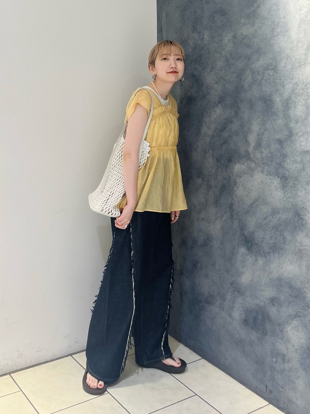 オレンジ系のシャツ/ブラウス、ブルー系のデニムパンツ、ホワイト系のハンドバッグを着用したレディースの夏コーディネートの2枚目の写真