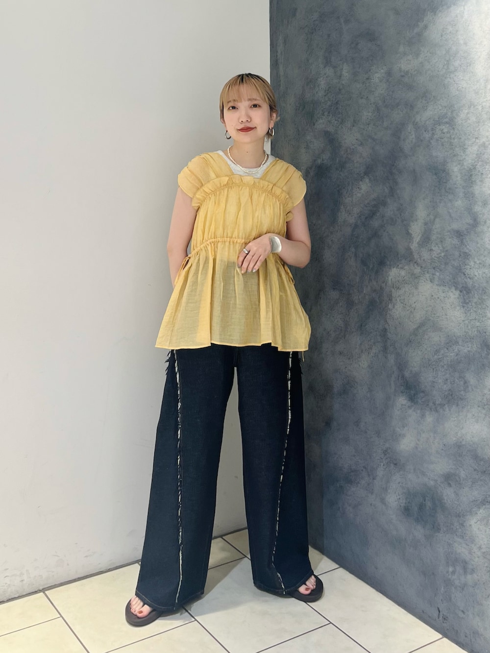 オレンジ系のシャツ/ブラウス、ブルー系のデニムパンツ、ホワイト系のハンドバッグを着用したレディースの夏コーディネートの3枚目の写真