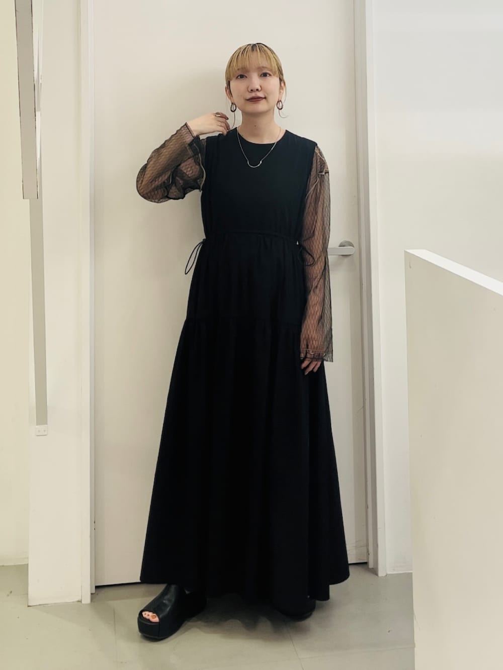 ブラック系のワンピース、ブラック系のニット/セーター、ブラック系のサンダルを着用したレディースの春コーディネートの2枚目の写真