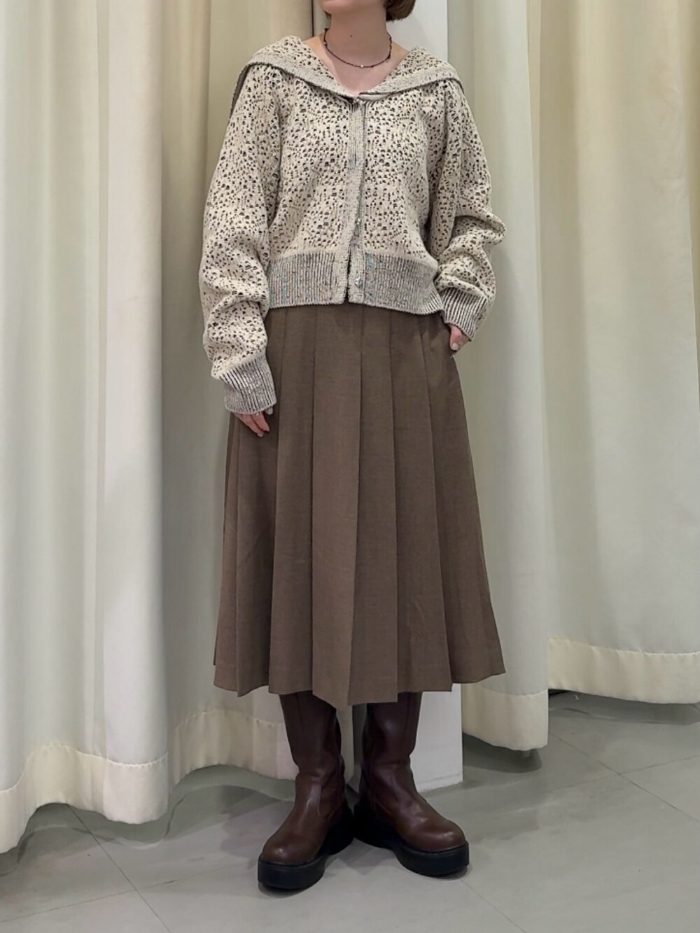 ホワイト系のニット/セーター、ブラウン系のスカート、ブラウン系のブーツを着用したレディースの秋コーディネートの3枚目の写真