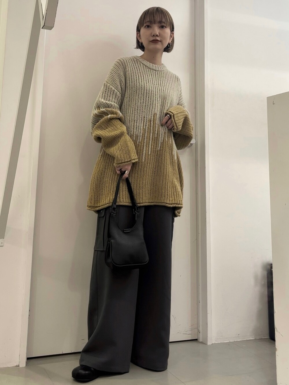 グレー系のニット/セーター、グレー系のその他パンツ、ブラック系のハンドバッグを着用したレディースの冬コーディネートの2枚目の写真