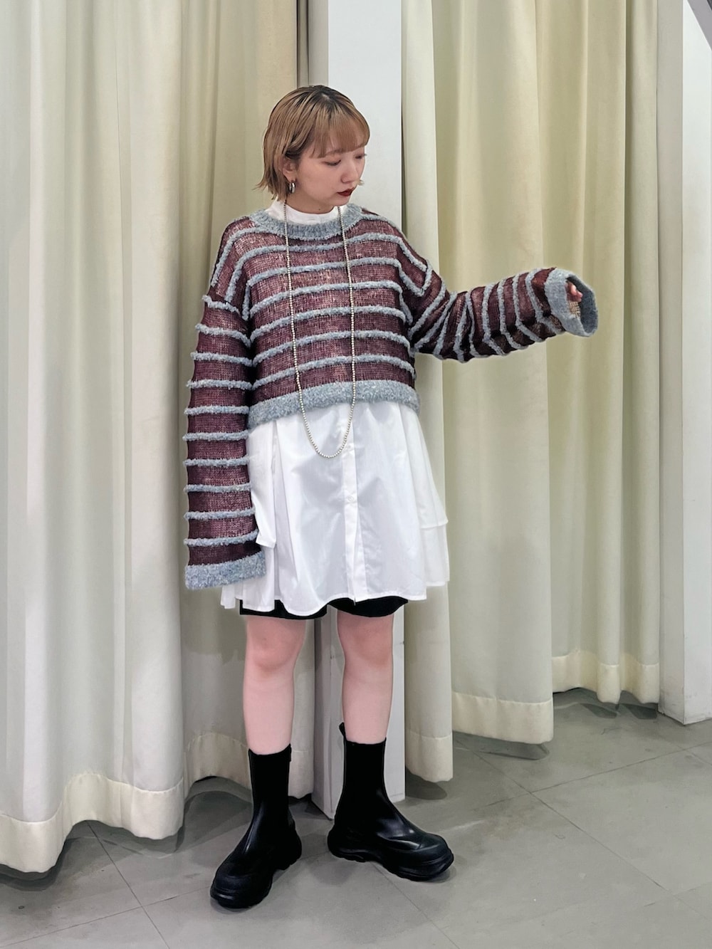 ブルー系のニット/セーター、ホワイト系のワンピース、ブラック系のブーツを着用したレディースの秋コーディネートの4枚目の写真