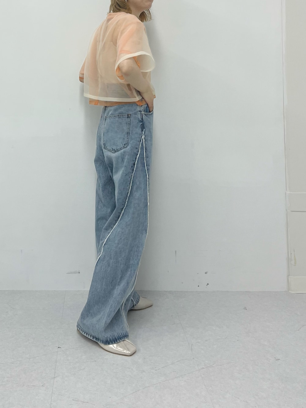 オレンジ系のTシャツ/カットソー、ブルー系のデニムパンツを着用したレディースの春コーディネートの4枚目の写真