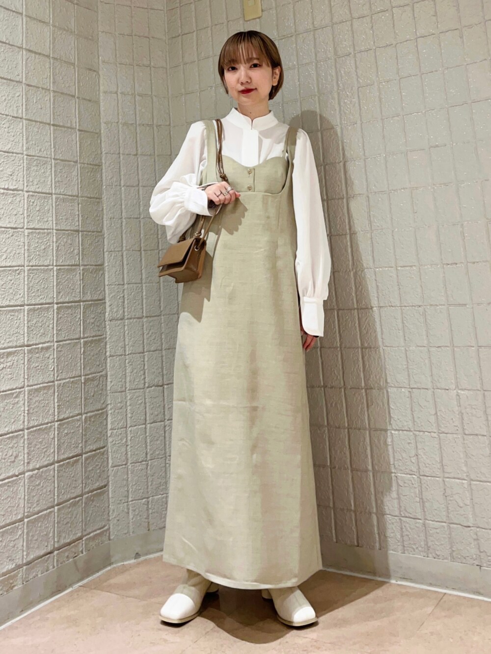 ベージュ系のワンピース、ホワイト系のシャツ/ブラウス、ホワイト系のブーツを着用したレディースの冬コーディネートの2枚目の写真