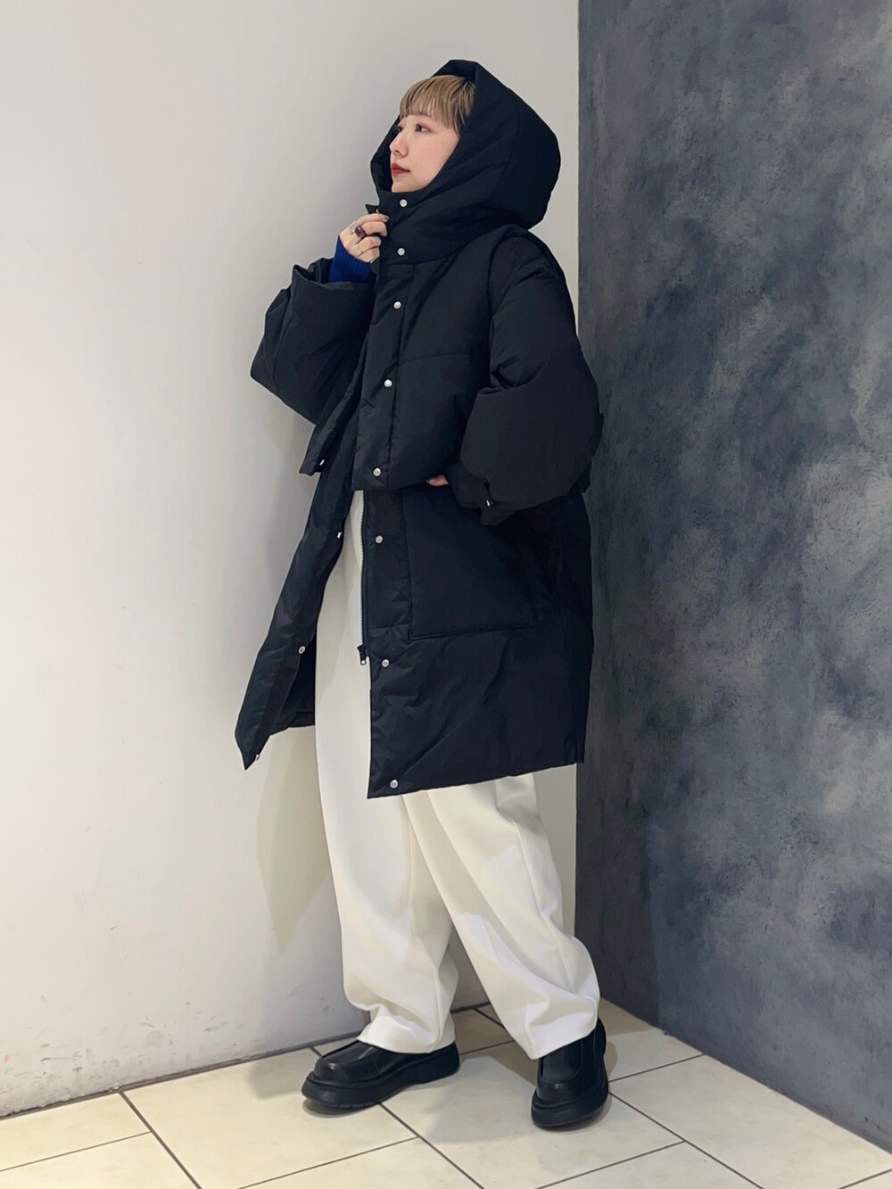 ブラック系のダウンジャケット/コート、ホワイト系のその他パンツ、ブルー系のニット/セーターを着用したレディースの冬コーディネートの3枚目の写真