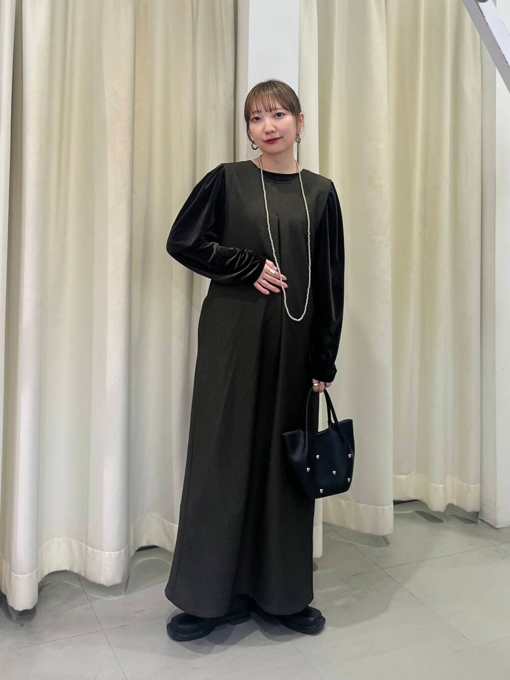 ブラック系のショルダーバッグ、ブラウン系のワンピース、ブラウン系のTシャツ/カットソーを着用したレディースの冬コーディネートの2枚目の写真