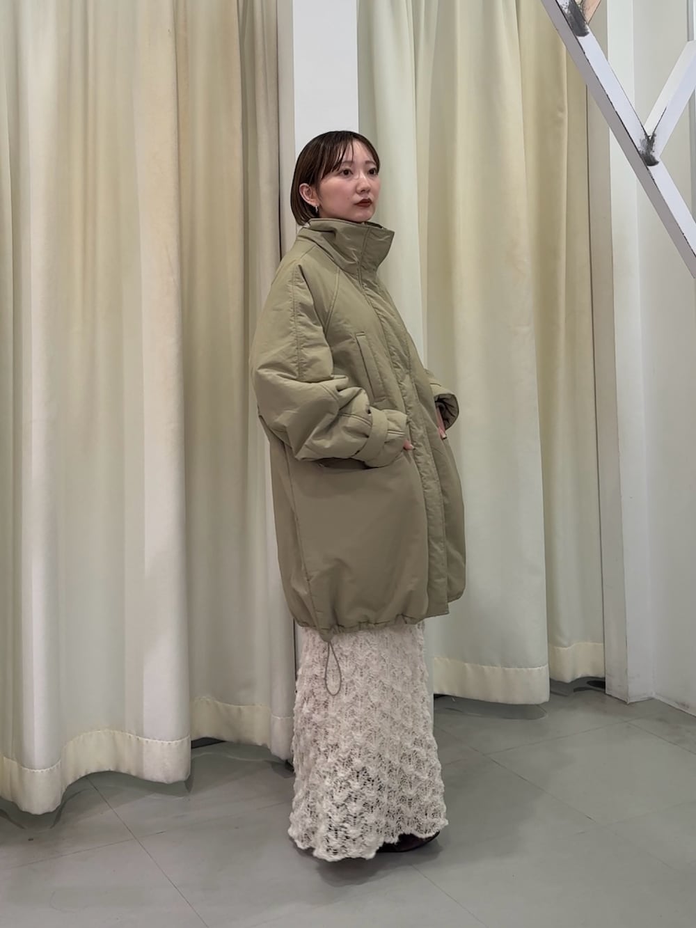 グリーン系のダウンジャケット/コート、ホワイト系のスカート、ブラウン系のスニーカーを着用したレディースの秋コーディネートの2枚目の写真