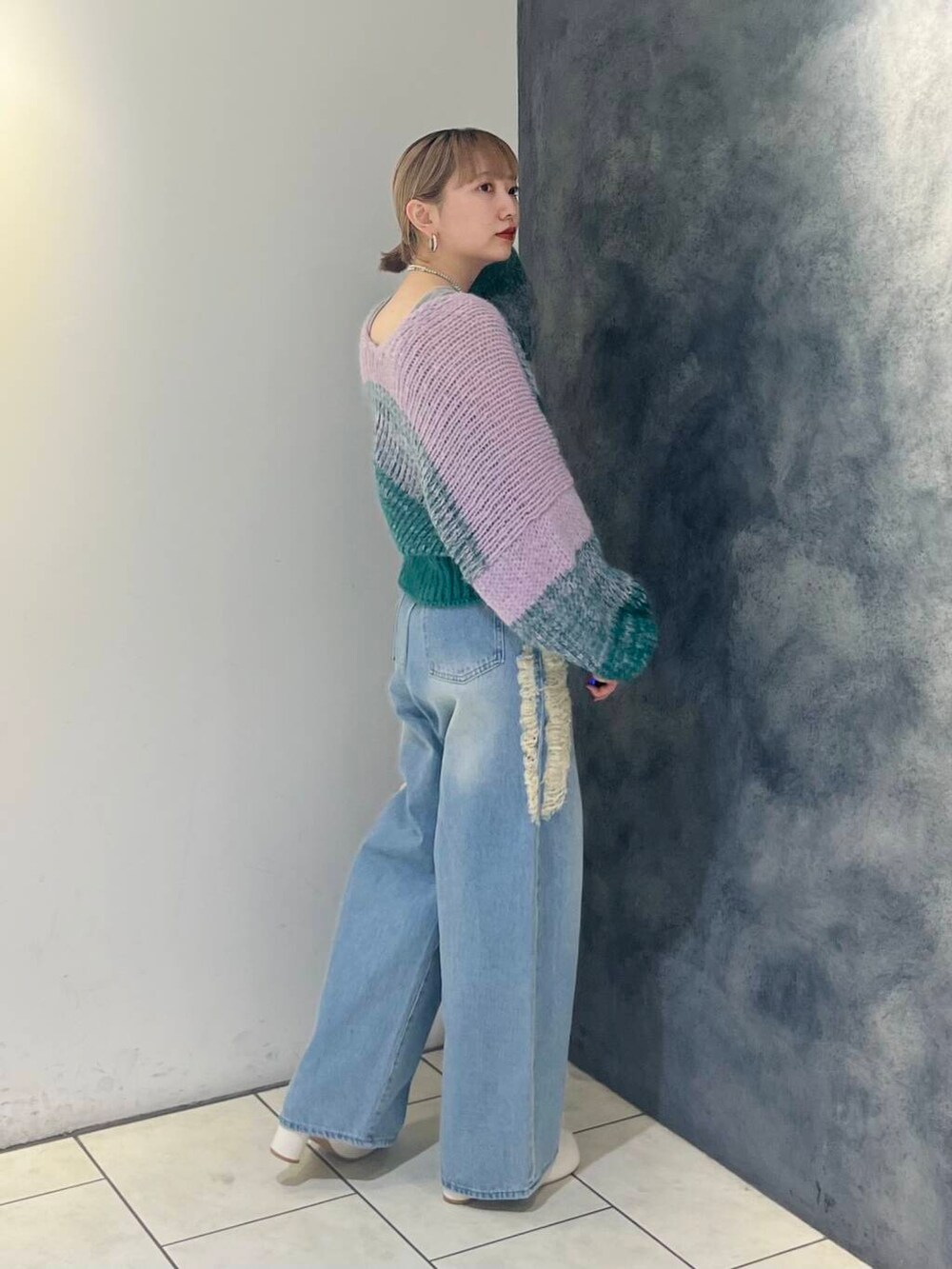 ブルー系のデニムパンツ、ホワイト系のブーツ、グレー系のタンクトップを着用したレディースの秋コーディネートの4枚目の写真