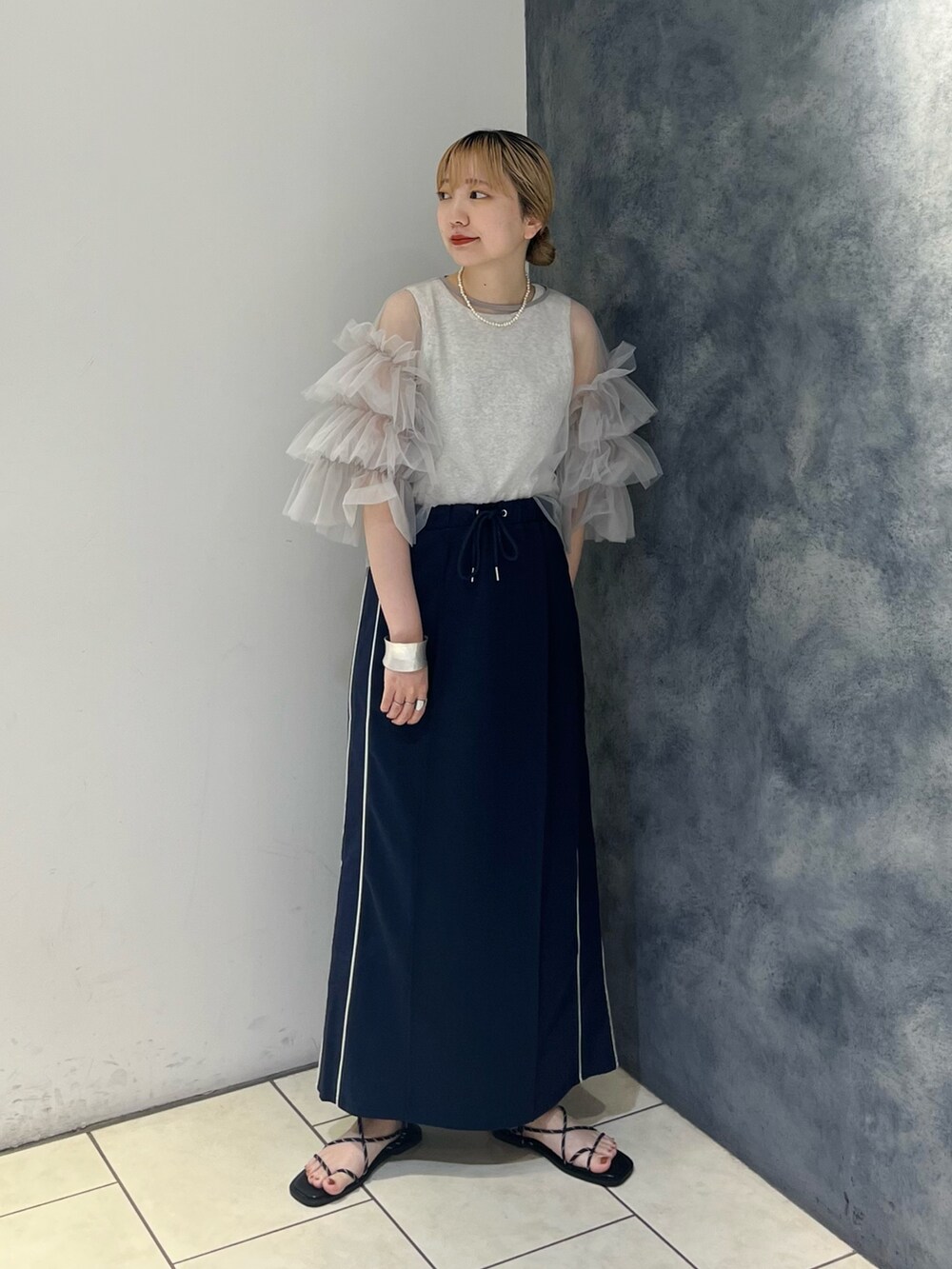 グレー系のシャツ/ブラウス、ベージュ系のタンクトップ、ブラック系のサンダルを着用したレディースの夏コーディネートの2枚目の写真