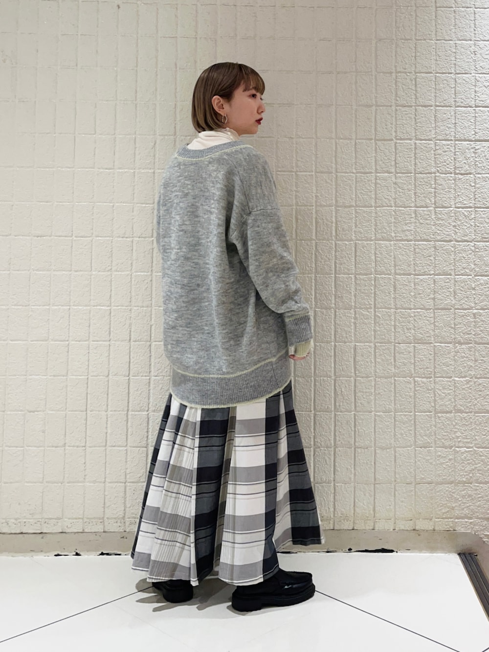 グレー系のカーディガン/ボレロ、ブラック系のスカート、ホワイト系のTシャツ/カットソーを着用したレディースの秋コーディネートの2枚目の写真