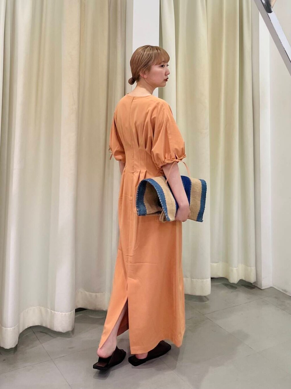 オレンジ系のワンピース、ブラウン系のサンダル、その他のトートバッグを着用したレディースの夏コーディネートの4枚目の写真