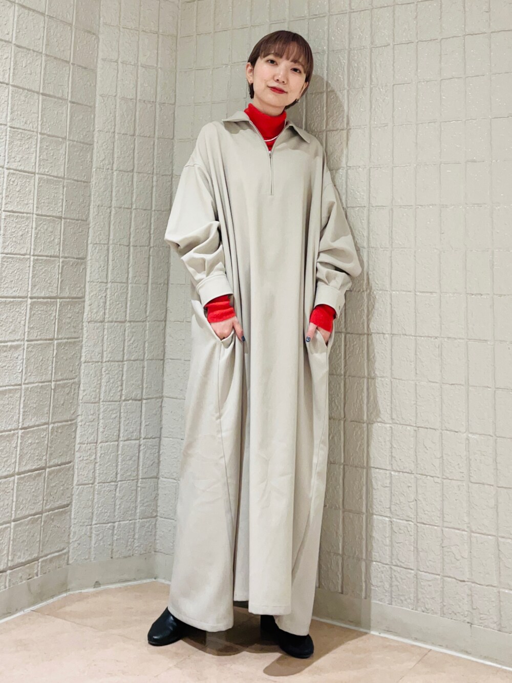 グレー系のワンピース、オレンジ系のニット/セーターを着用したレディースの冬コーディネートの2枚目の写真