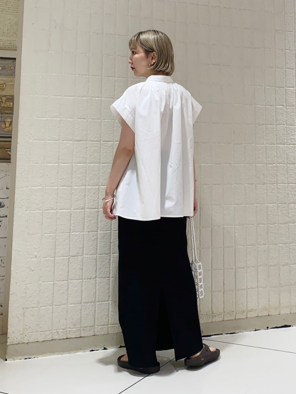 ホワイト系のシャツ/ブラウス、ブラック系のスカート、ホワイト系のハンドバッグを着用したレディースの夏コーディネートの3枚目の写真