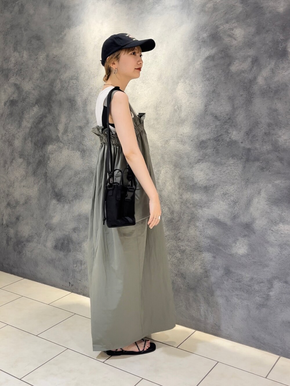 グリーン系のワンピース、ブラック系のショルダーバッグ、ベージュ系のタンクトップを着用したレディースの夏コーディネートの4枚目の写真