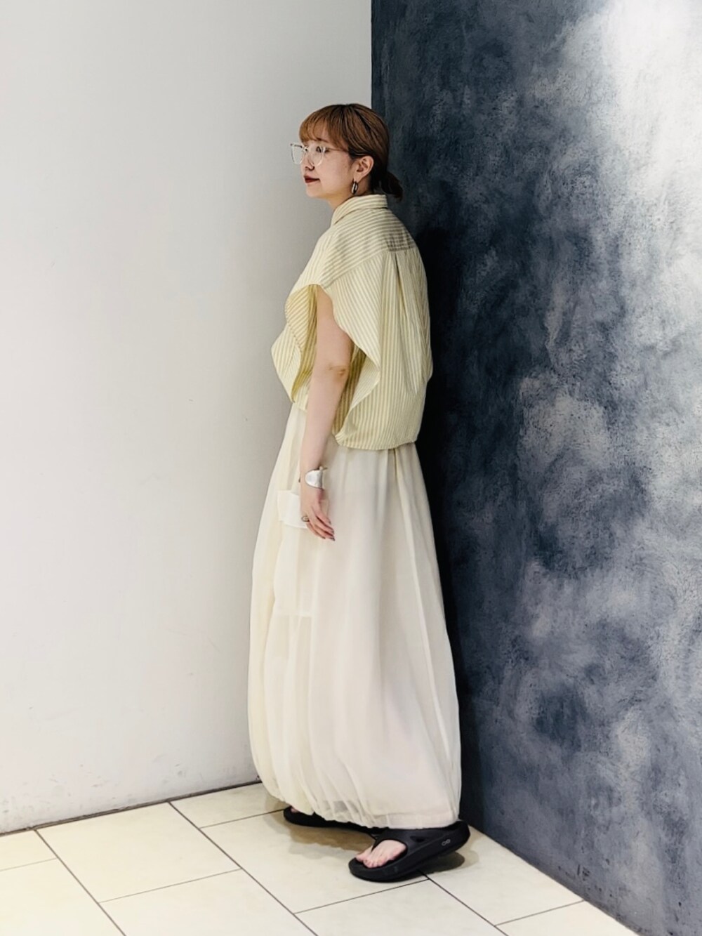 イエロー系のシャツ/ブラウス、ホワイト系のスカート、ブラウン系のサンダルを着用したレディースの春コーディネートの3枚目の写真