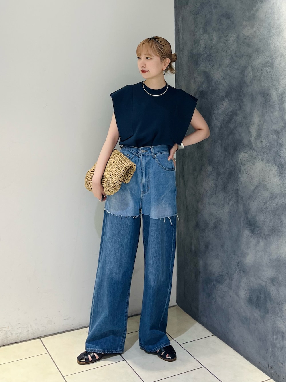 ブルー系のデニムパンツ、ブルー系のニット/セーター、ベージュ系のトートバッグを着用したレディースの夏コーディネートの2枚目の写真