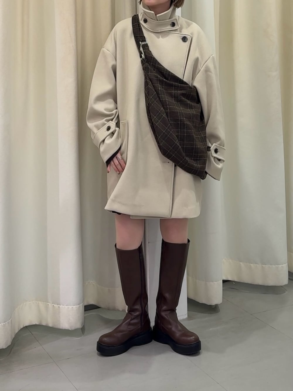 ベージュ系のその他アウター、ブラウン系のブーツ、ブラウン系のトートバッグを着用したレディースの秋コーディネートの2枚目の写真