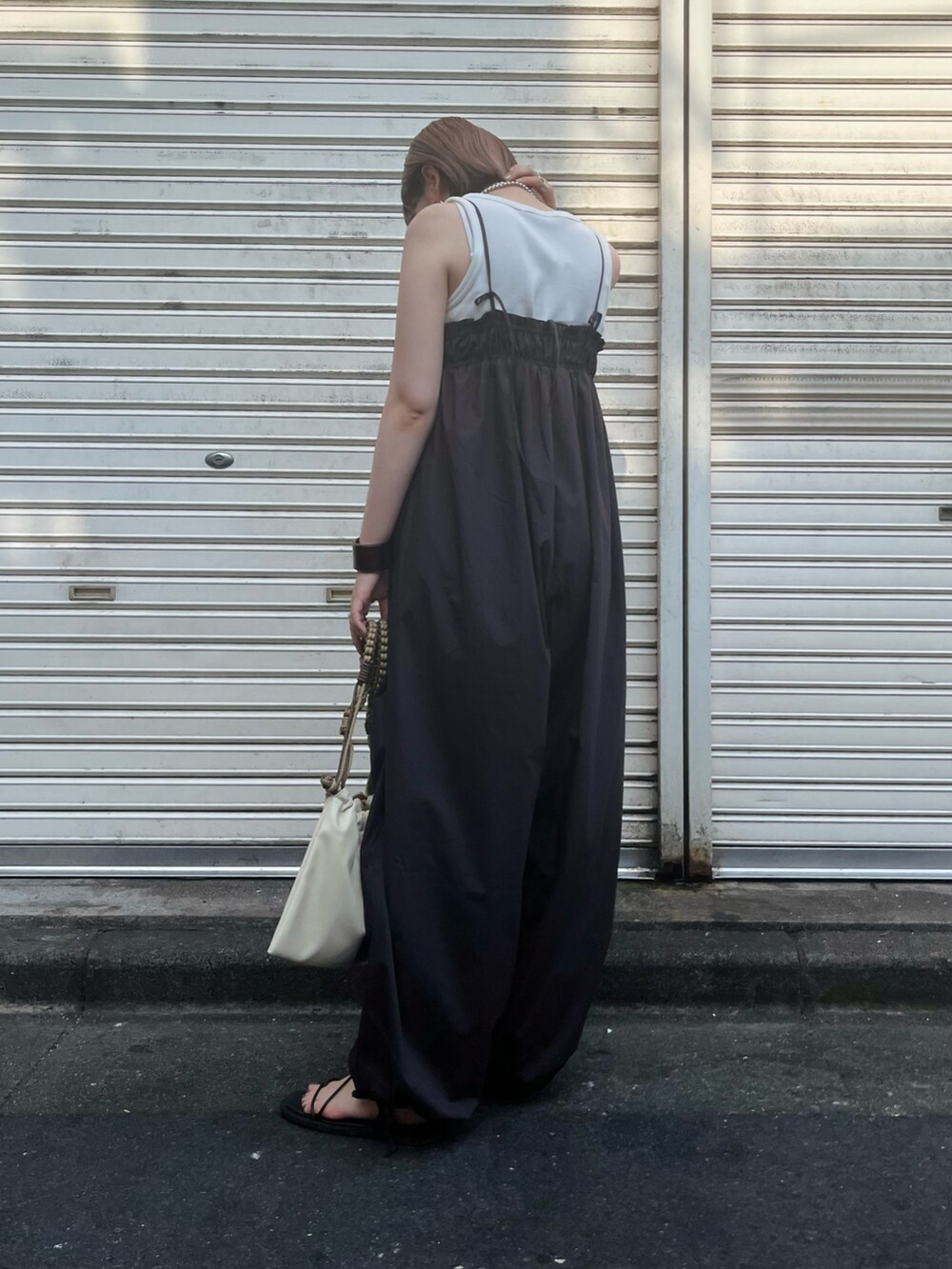 グレー系のサロペット/オーバーオール、ホワイト系のタンクトップ、ブラック系のサンダルを着用したレディースの夏コーディネートの4枚目の写真