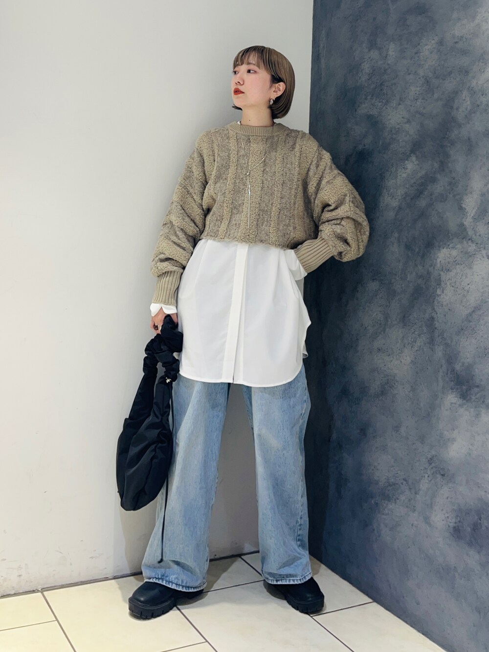 ベージュ系のニット/セーター、ホワイト系のシャツ/ブラウス、ブルー系のデニムパンツを着用したレディースの冬コーディネートの2枚目の写真
