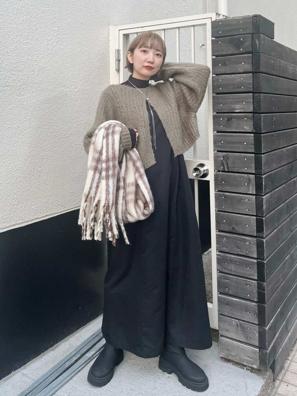 グリーン系のワンピース、ブラック系のブーツ、ホワイト系のマフラーを着用したレディースの冬コーディネートの3枚目の写真