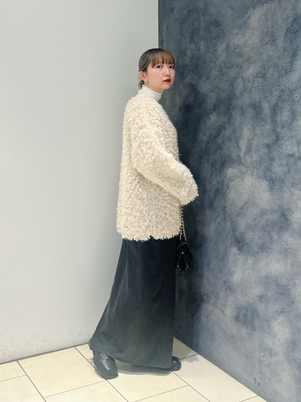 ブラック系のスカート、ホワイト系のカーディガン/ボレロ、ホワイト系のTシャツ/カットソーを着用したレディースの冬コーディネートの2枚目の写真
