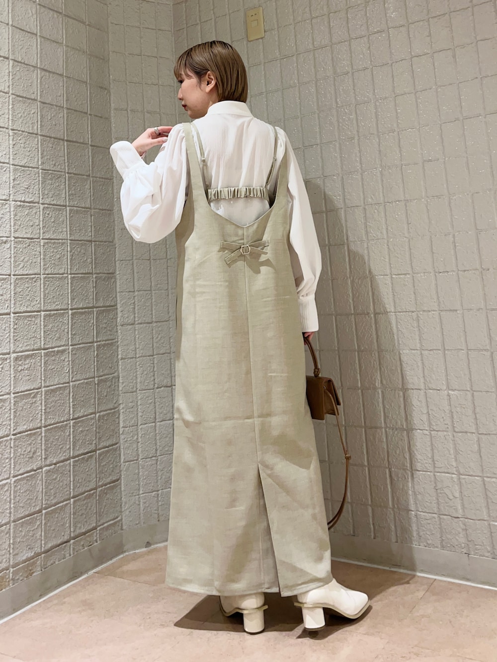 ベージュ系のワンピース、ホワイト系のシャツ/ブラウス、ホワイト系のブーツを着用したレディースの冬コーディネートの3枚目の写真