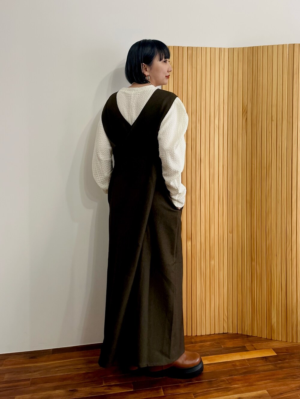 ブラウン系のワンピース、ホワイト系のTシャツ/カットソー、ブラウン系のブーツを着用したレディースの秋コーディネートの3枚目の写真