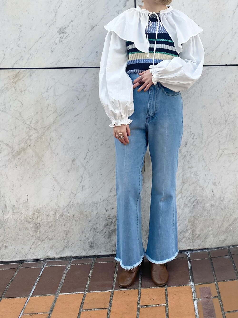 ブルー系のデニムパンツ、ホワイト系のシャツ/ブラウス、ブルー系のニット/セーターを着用したレディースの冬コーディネートの2枚目の写真