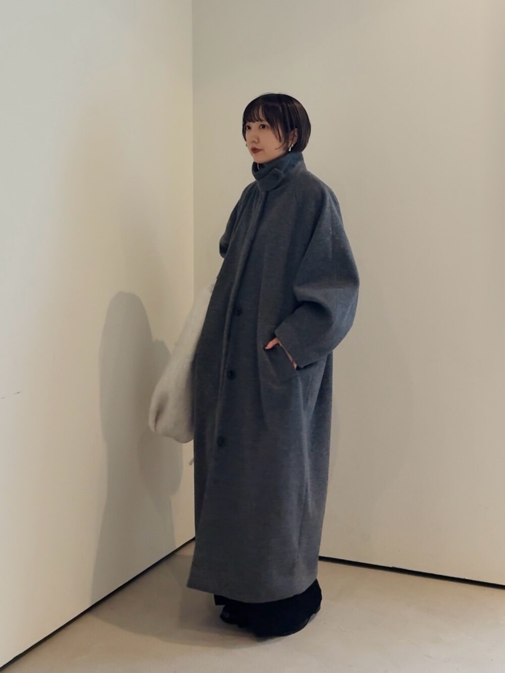 グレー系のステンカラーコート、ブラック系のマフラーを着用したレディースの秋コーディネートの2枚目の写真