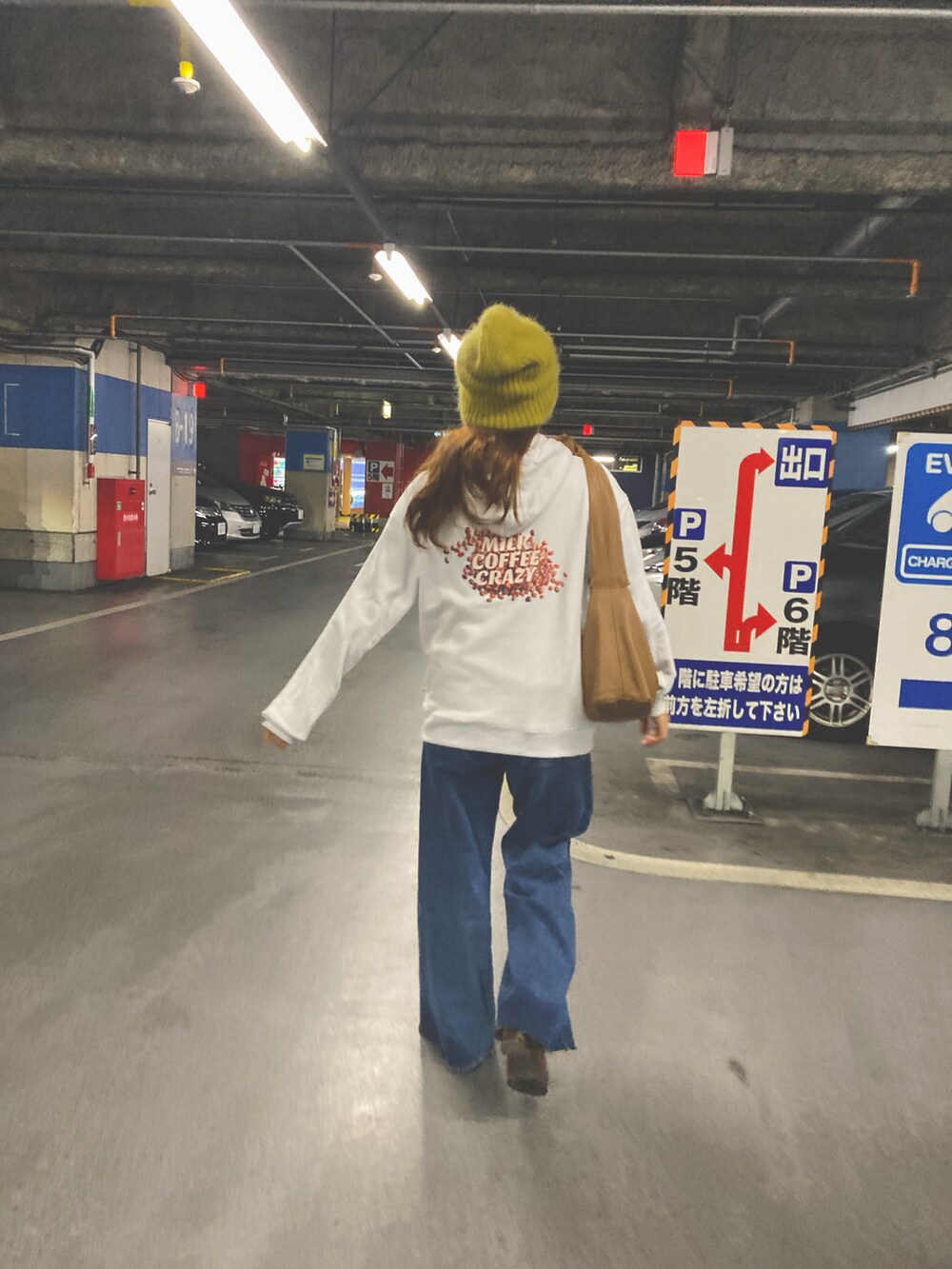 ブルー系のデニムパンツ、ホワイト系のパーカー、ブラウン系のショルダーバッグを着用したレディースの冬コーディネートの2枚目の写真