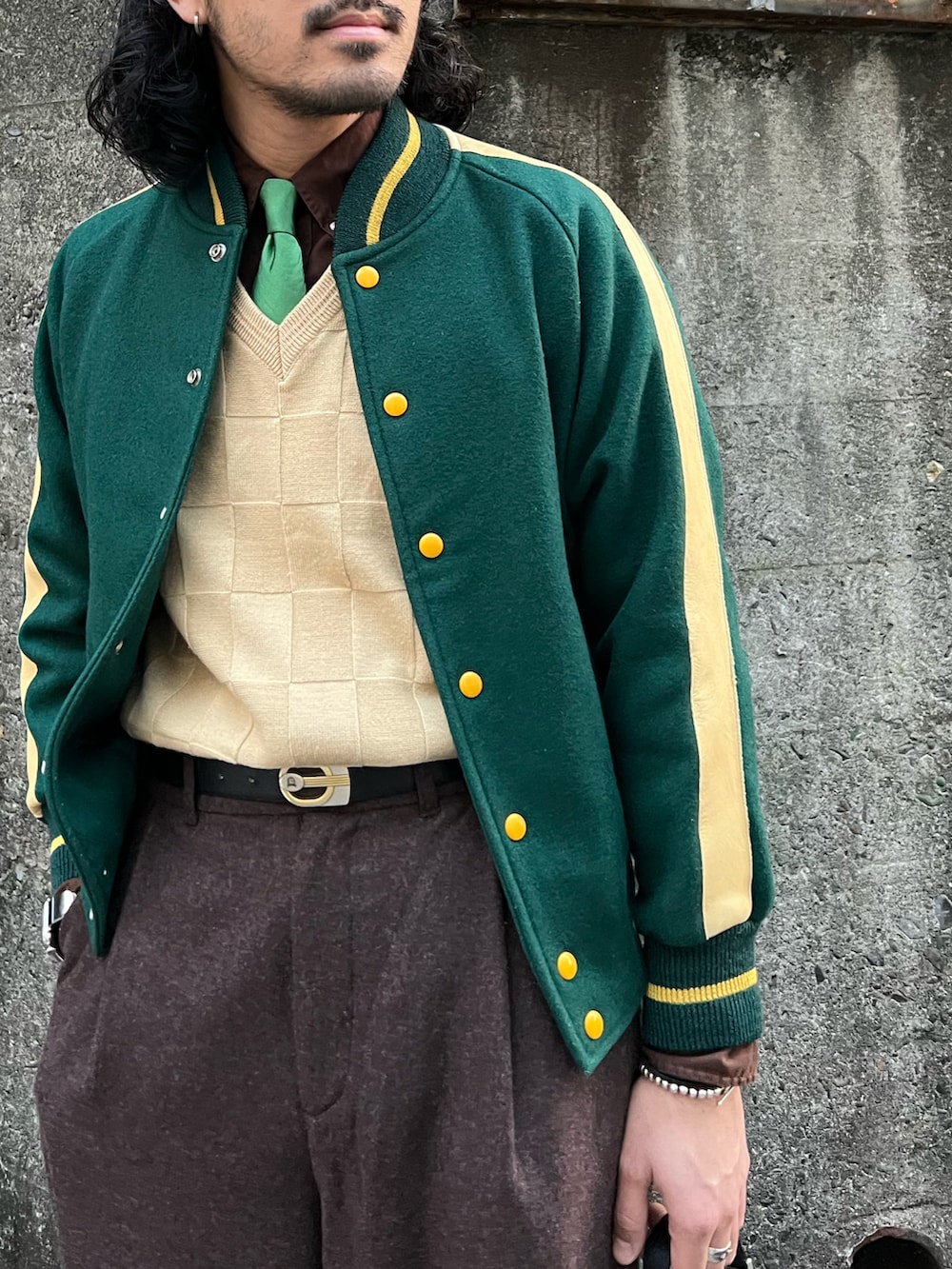 グリーン系のスタジャン、ベージュ系のニット/セーター、ブラウン系のシャツ/ブラウスを着用したメンズの冬コーディネートの2枚目の写真