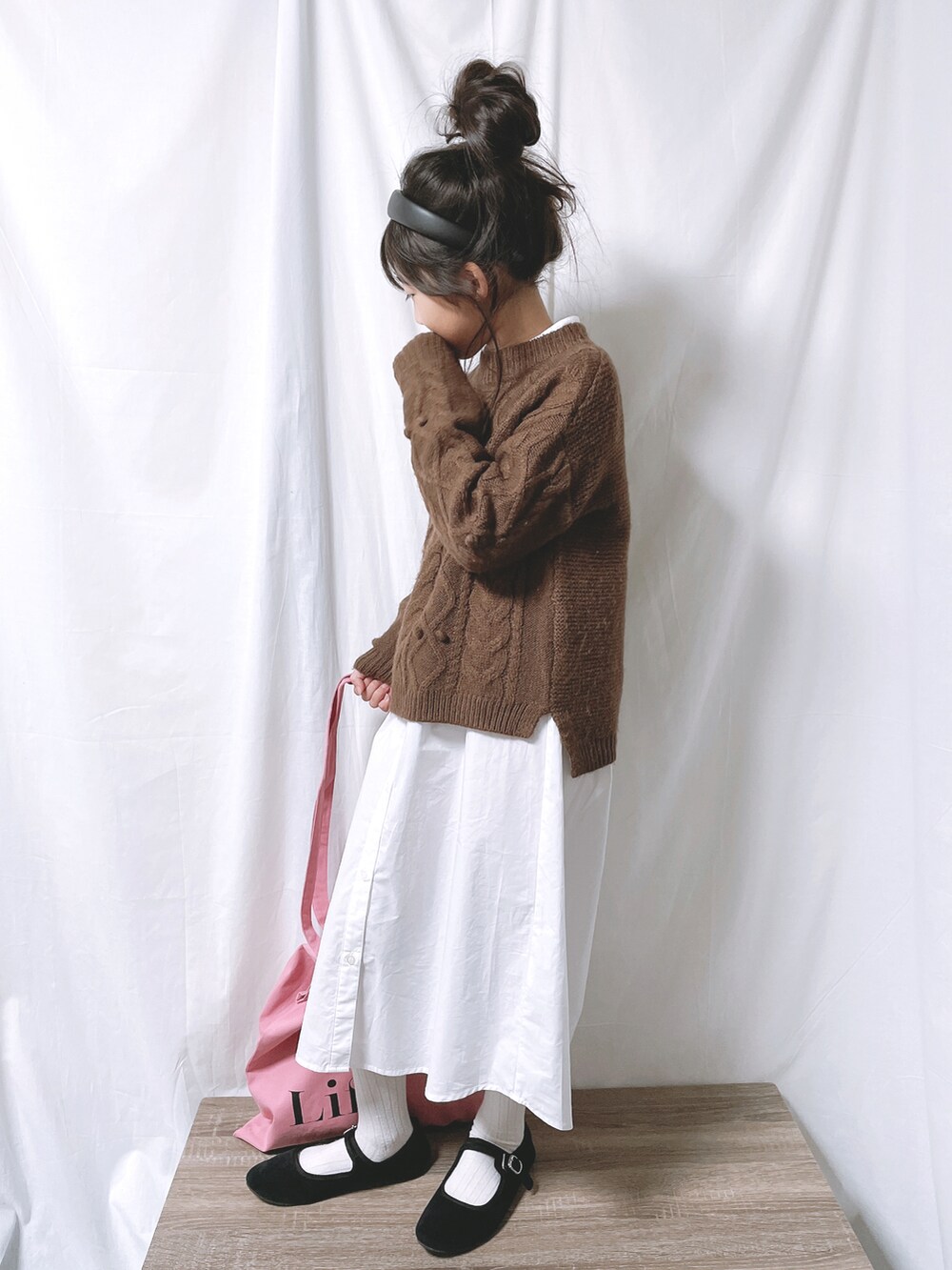 ピンク系のトートバッグ、ブラウン系のニット/セーター、ベージュ系のワンピースを着用したキッズの秋コーディネートの2枚目の写真