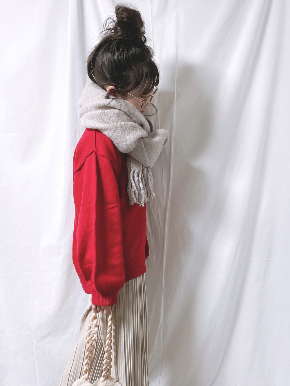 レッド系のニット/セーター、ベージュ系のその他パンツ、ホワイト系のバッグを着用したキッズの冬コーディネートの3枚目の写真