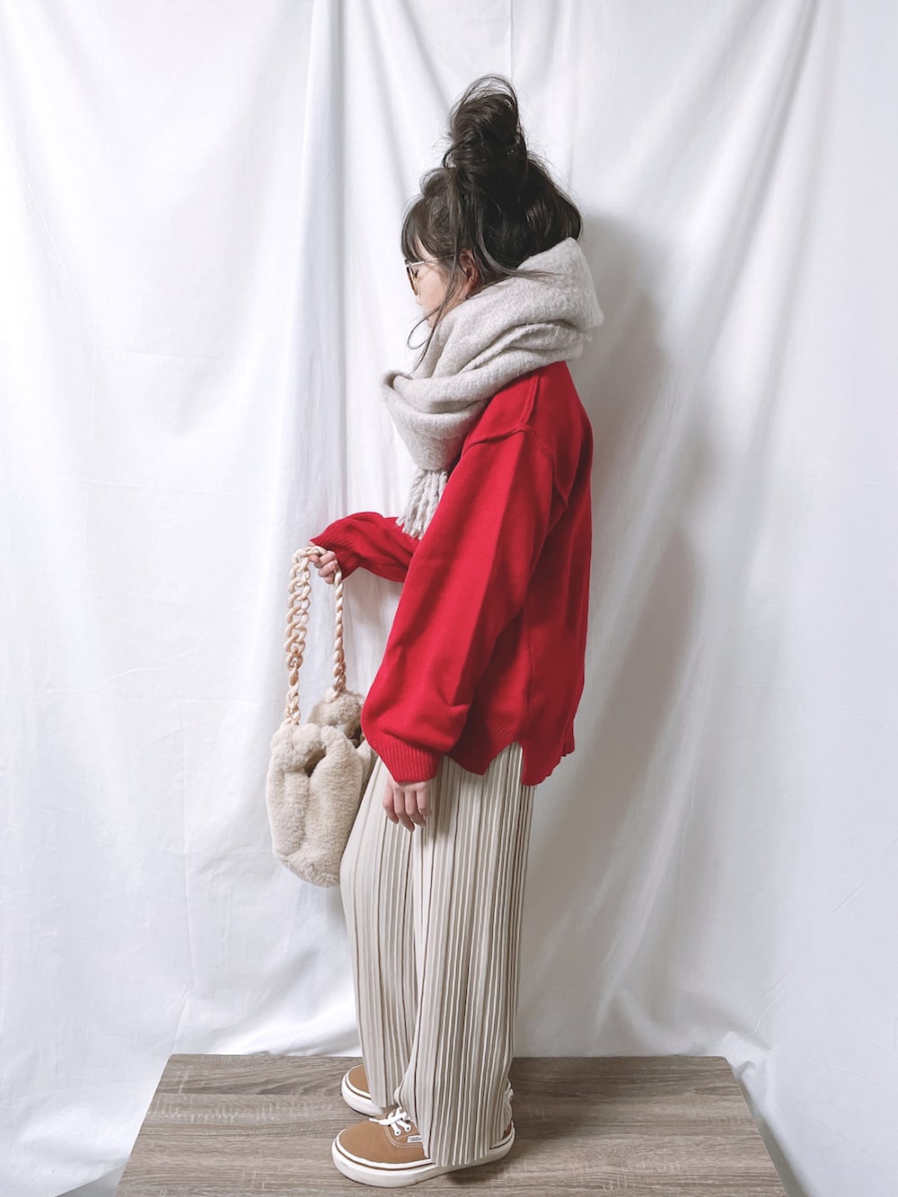 レッド系のニット/セーター、ベージュ系のその他パンツ、ホワイト系のバッグを着用したキッズの冬コーディネートの2枚目の写真