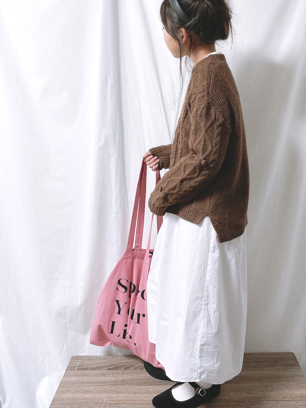 ピンク系のトートバッグ、ブラウン系のニット/セーター、ベージュ系のワンピースを着用したキッズの秋コーディネートの3枚目の写真