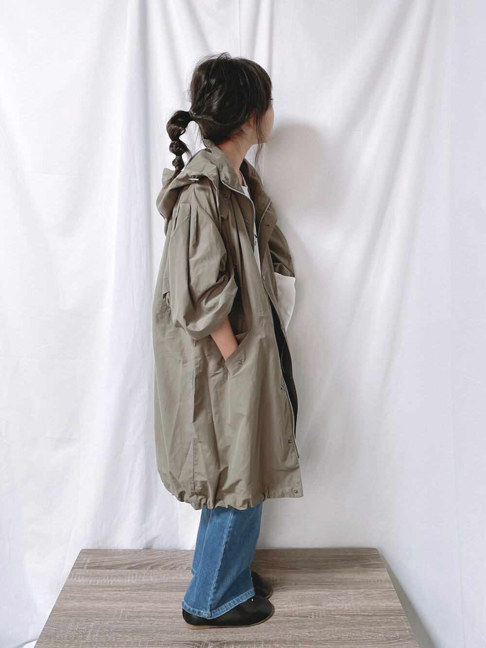 グリーン系のモッズコート、ブルー系のデニムパンツ、ホワイト系のトートバッグを着用したキッズの秋コーディネートの3枚目の写真